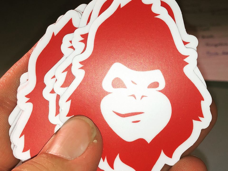 Red die-cut MAD Monkey vinyl stickers held in a hand